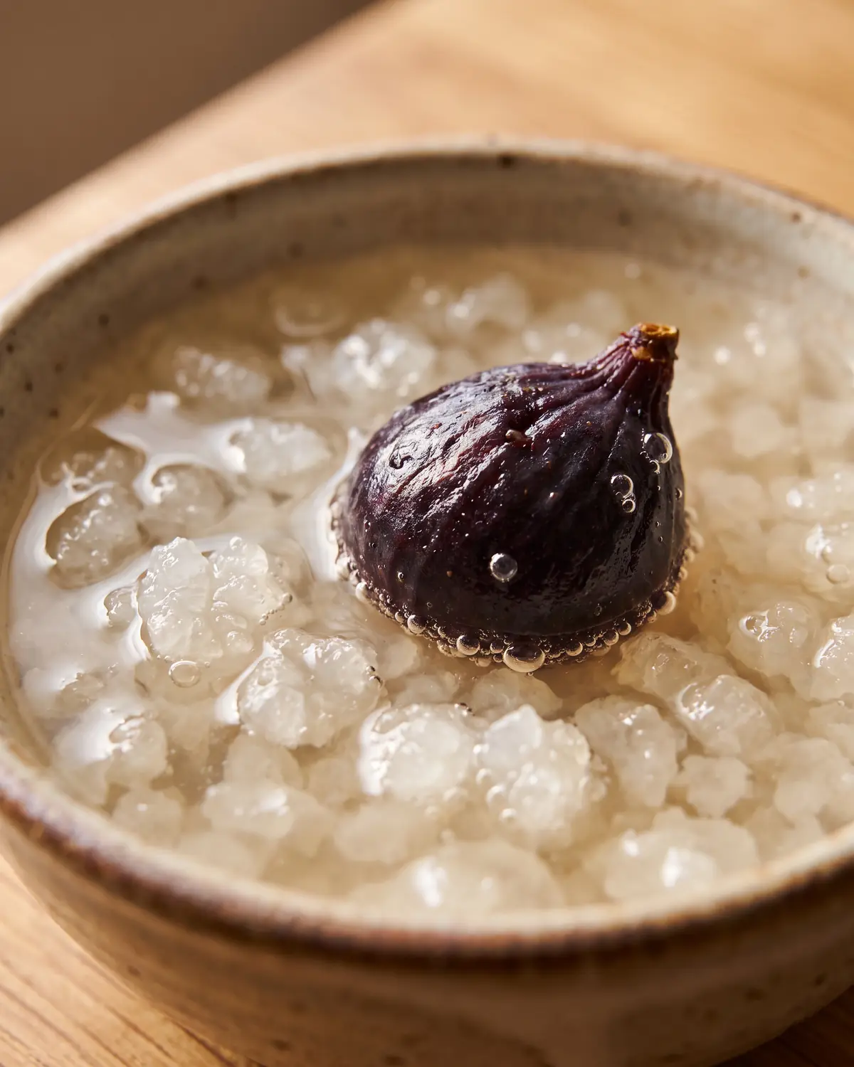 Nahaufnahme einer rehydrierten Trockenfeige &uuml;ber Wasserkefir-Kristallen mit feinen Bl&auml;schen