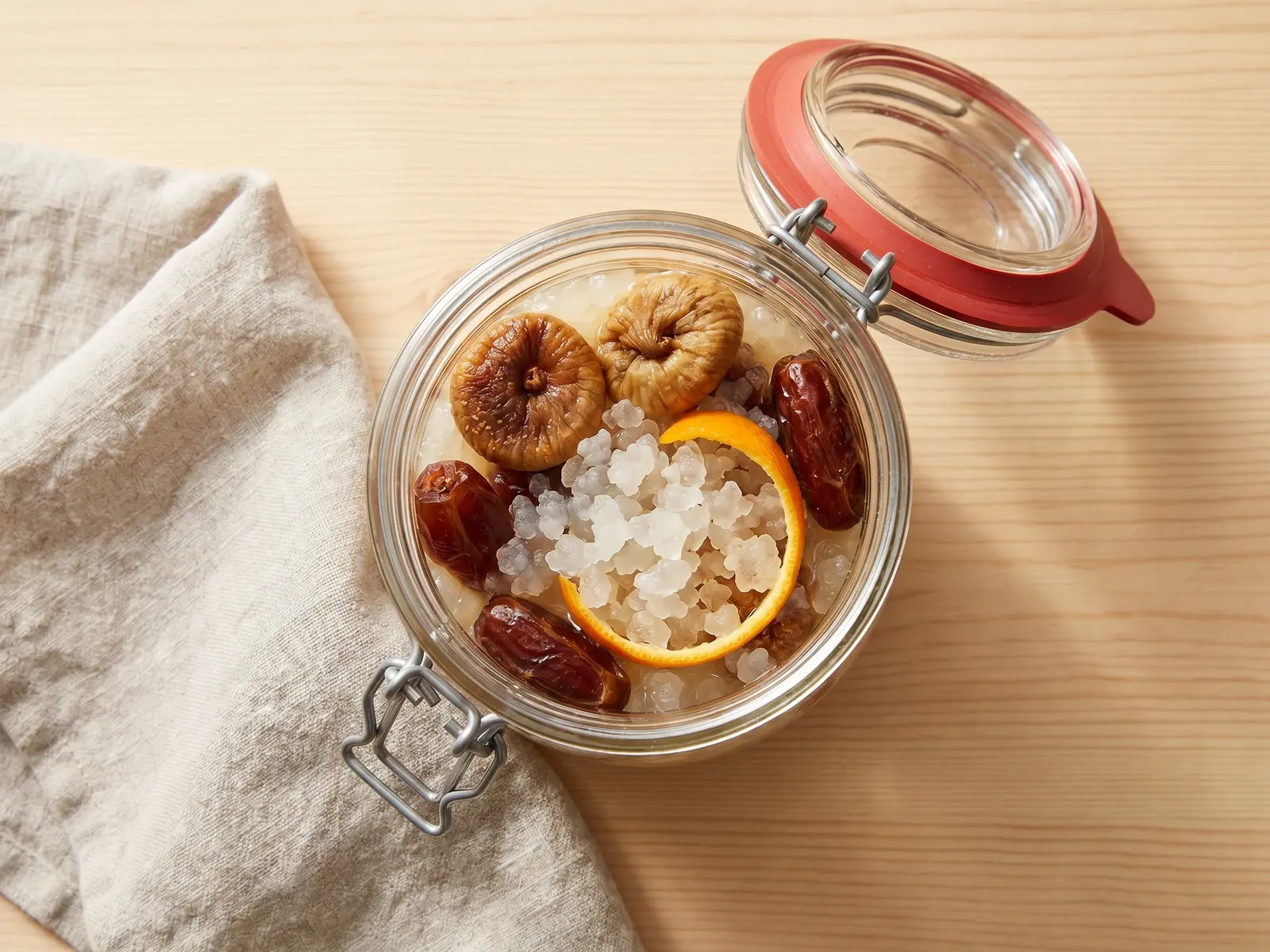 Glas mit Wasserkefir in der zweiten Fermentation, Higen, Datteln und Orangenschale im Ansatz