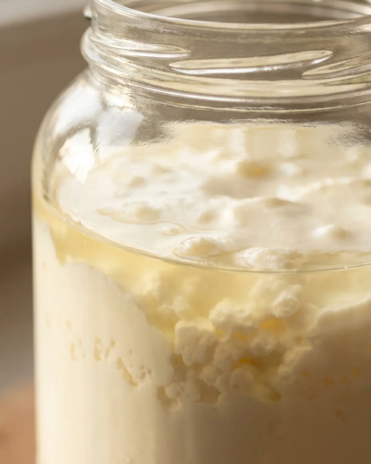 quark fermentiert Nahaufnahme eines Kefirglases mit klarer Linie zwischen Molke und cremiger Schicht nach der Fermentation